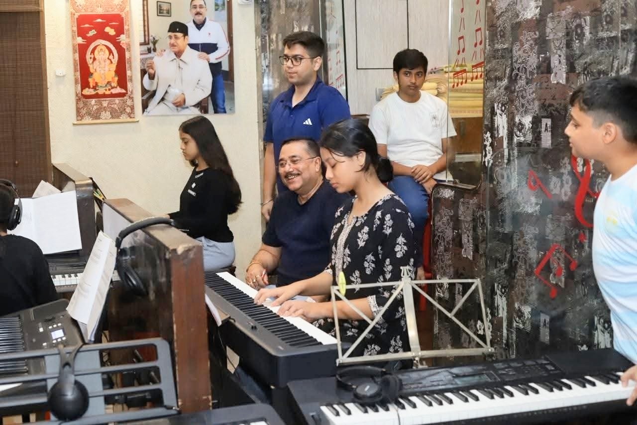 A student playing the piano alongside her teacher at Piano Kids