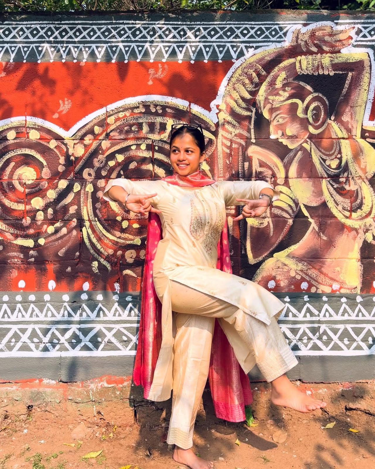 Rodali Bora striking a dance pose in front of a painted mural